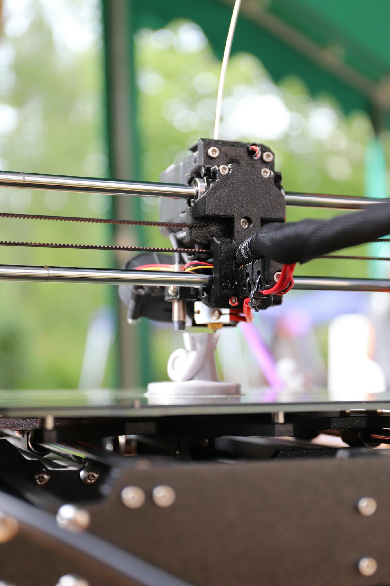 Detailed view of a 3D printer creating an object outdoors, highlighting innovation and precision.